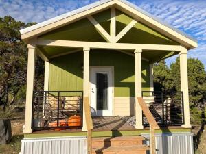 a small green house with a porch and a pumpkin at Cozy Tiny Home in the Hills in Fischer
