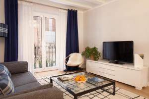 ein Wohnzimmer mit einem Sofa und einem TV in der Unterkunft Click&Flat Stylish Torrijos in Barcelona