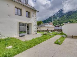 ein weißes Haus mit einem grasbewachsenen Hof neben einem Gebäude in der Unterkunft Triplex 7p avec Terrasse, Parking et Casier à Skis - Centre de Cauterets, à 250m des Pistes - FR-1-401-173 in Cauterets