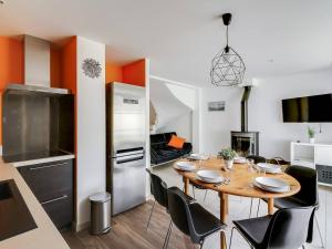 eine Küche mit einem Tisch mit Stühlen und einem Kühlschrank in der Unterkunft Triplex 7p avec Terrasse, Parking et Casier à Skis - Centre de Cauterets, à 250m des Pistes - FR-1-401-173 in Cauterets