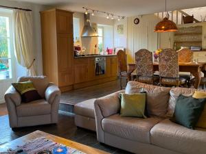 La Lande في Bricquebec: غرفة معيشة مع أريكة وكراسي ومطبخ