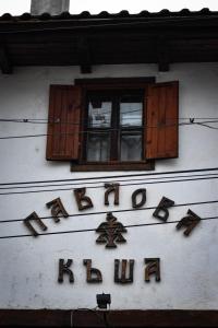 un panneau sur le côté d'un bâtiment avec une fenêtre dans l'établissement Хотел-механа Павлова къща, à Chiprovtsi