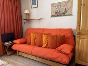 ein orangefarbenes Sofa mit Kissen im Wohnzimmer in der Unterkunft Appartement Montgenèvre, 1 pièce, 3 personnes - FR-1-330D-35 in Montgenèvre
