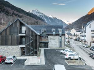 a large building with cars parked in a parking lot at Doux Duplex à 6 dans Saint-Lary-Soulan - FR-1-296-291 in Saint-Lary-Soulan