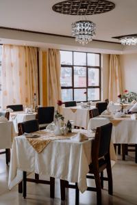 a restaurant with white tables and chairs and windows at Saab Royale Hotel in Nairobi