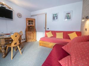 Una sala de estar con un sofá rojo y una mesa. en Appartement cosy 4 pers, Animaux acceptés, Parking dispo - FR-1-291-845, en Valmorel