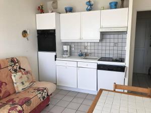 a kitchen with white cabinets and a couch in a room at Appartement Royan, 2 pièces, 4 personnes - FR-1-494-89 in Royan