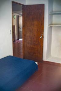 1 dormitorio con puerta de madera y cama azul en Casa para 4 pers. con entrada de auto y parrillero, en Piriápolis