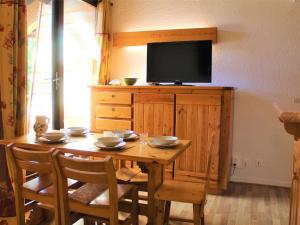 une table en bois avec des chaises et une télévision sur une armoire dans l'établissement Appartement Vars, 2 pièces, 6 personnes - FR-1-330B-173, à Vars