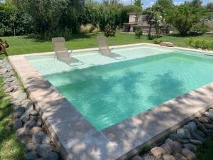 a swimming pool with two chairs in a yard at Casa Terra in Ciudad Lujan de Cuyo