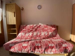 a bedroom with a bed with a red and white quilt at Appartement Praz-sur-Arly, 1 pièce, 4 personnes - FR-1-603-28 in Praz-sur-Arly