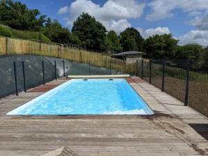 uma grande piscina azul com um deque de madeira em Domaine du Martinaa em Saint-Martin-de-la-Lieue