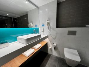 uma casa de banho com um lavatório, um WC e um espelho. em Holiday Inn Express - Madrid - Airport, an IHG Hotel em Madri