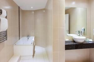 uma casa de banho com uma banheira e um lavatório e uma banheira em Holiday Inn Norwich North, an IHG Hotel em Norwich