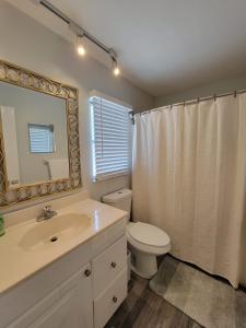 uma casa de banho com um WC, um lavatório e um espelho. em Walk To Siesta Beach, Restaurants, Shopping & More! em Sarasota