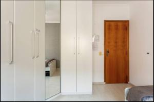 Pokój z białymi szafkami i drewnianymi drzwiami w obiekcie Apartamento compartilhado, no Gonzaga em Santos w mieście Santos
