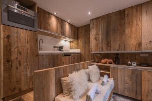 cocina con paneles de madera en las paredes y sofá con asiento en Studio Cristallin - Welkeys en Megève