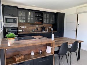 a kitchen with black cabinets and a wooden counter top at Maison 3* à Trébeurden: jardin clos, 2 chambres, proche plage et sentiers - FR-1-542-46 in Trébeurden
