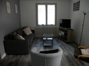 een woonkamer met een bank en een tv bij Coquelicot, Entre Volcans d Auvergne et Sancy, Orcival. in Orcival