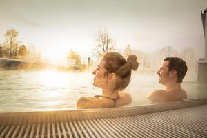 a man and woman swimming in a hot tub at Appartement Sunnseit - Kitzbüheler Alpen in Sankt Johann in Tirol