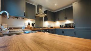 cocina con armarios azules y encimera de madera en Saxon Corner: BRAND NEW 3 bedroom House en Emsworth