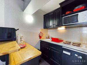 a kitchen with black cabinets and a microwave at Studio Montvalezan-La Rosière, 1 pièce, 4 personnes - FR-1-398-639 in Montvalezan