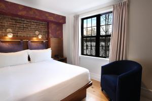 a bedroom with a bed and a chair and a window at Hotel Scherman in New York
