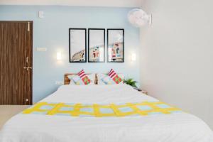 um quarto com uma grande cama branca com toques amarelos em Goroomgo Dream LIne Kalikapur Kolkata em Calcutá