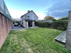 a backyard of a house with a grass yard at Cheerful 2 bed house on Causeway Coastal Route with parking in Whiteabbey