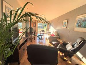 una sala de estar con sofás y una planta en Maison Pleuven, 7 pièces, 7 personnes - FR-1-481-99 en Pleuven