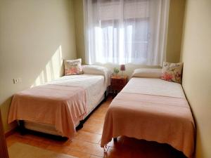 two beds in a room with a window at Apto 200 mts playa Lapamán, terraza vistas al mar in Bueu