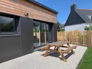 a wooden picnic table in front of a building at Maison 3* à Trébeurden: jardin clos, 2 chambres, proche plage et sentiers - FR-1-542-46 in Trébeurden