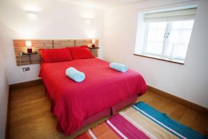 Un dormitorio con una gran cama roja con almohadas azules en Big Moo, en Llanrhyddlad