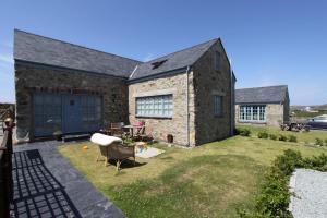 una casa de piedra con un patio con una silla en Big Moo, en Llanrhyddlad
