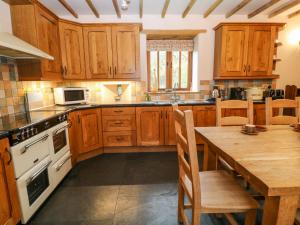 a large kitchen with wooden cabinets and a wooden table at Stone Barn in Holsworthy