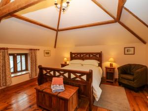 um quarto com uma cama grande e uma cadeira em Stone Barn em Holsworthy