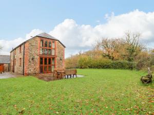 a brick house with a bench and a grass yard at Stone Barn in Holsworthy