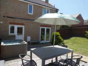 a picnic table with an umbrella and a hot tub at Cliffwalk Cottage in Portland