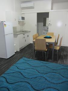 a kitchen with a table and chairs and a refrigerator at Urangan Motor Inn in Hervey Bay