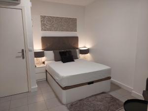 a small bedroom with a bed with white sheets and lamps at Apartamentos Rous - Solo adultos in Valencia