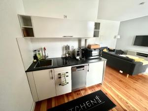 eine Küche mit weißen Schränken und ein Wohnzimmer in der Unterkunft Cityapartments Düsseldorf - Stresemannstraße in Düsseldorf