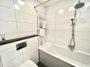 a white bathroom with a shower and a toilet at Vibehome Düsseldorf - Stresemannstraße in Düsseldorf