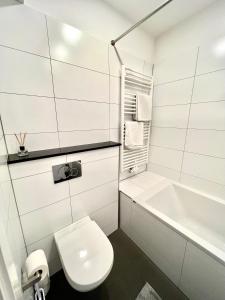a white bathroom with a toilet and a bath tub at Vibehome Düsseldorf - Stresemannstraße in Düsseldorf +4 photos
