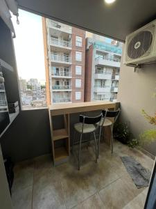 una cocina con 2 sillas y una barra y una ventana en 8M Monoambiente nuevo en el Centro de Rosario p 2 personas en Rosario