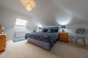 a bedroom with a bed and a chair at Maltings Lodge in Chelsworth