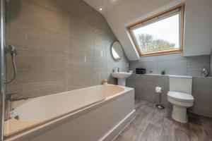 a bathroom with a tub and a toilet and a sink at Maltings Lodge in Chelsworth