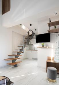 a white living room with stairs and a tv at San Giorgio Apartments Nikiti in Nikiti