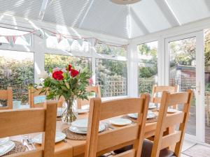 a dining room with a table with a vase of roses at Welsummer in Salcombe