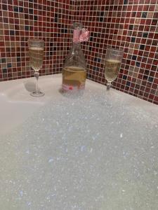 two glasses and a bottle of wine on a bath tub at City Home in Verona