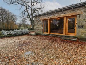 a stone house with large windows and a gravel yard at Ash Cottage in Skipton